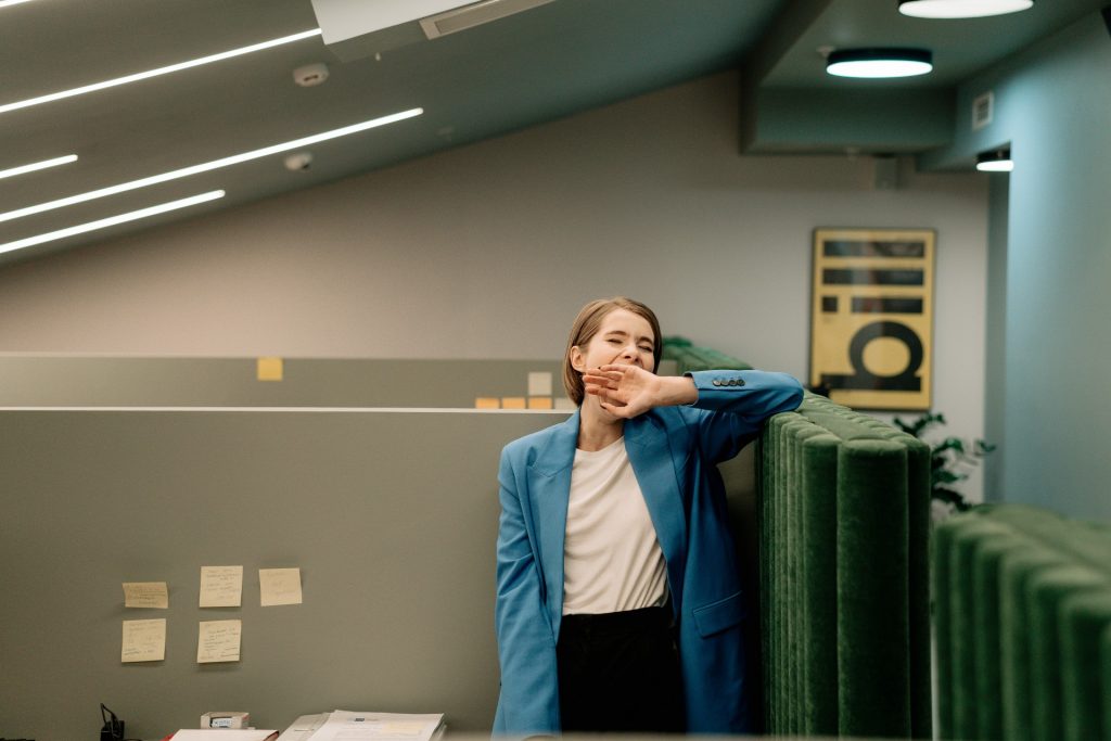 person in a suit blazer yawning in an office